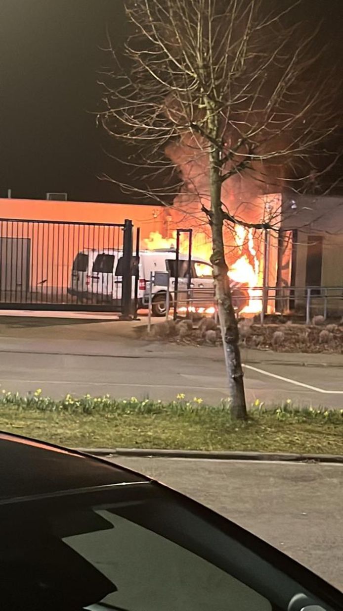 De molotvcocktails doen brand ontstaan aan enkele politievoertuigen én aan de gevel van het gebouw.