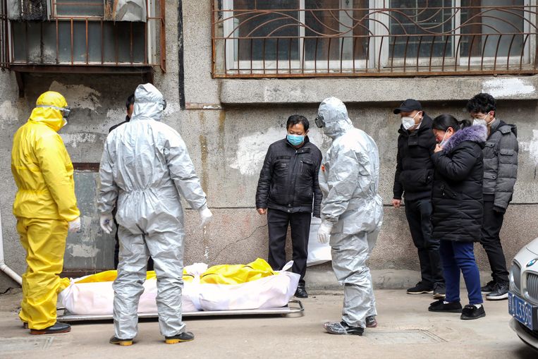 Een coronaslachtoffer wordt uit zijn huis in Wuhan gedragen. Beeld EPA