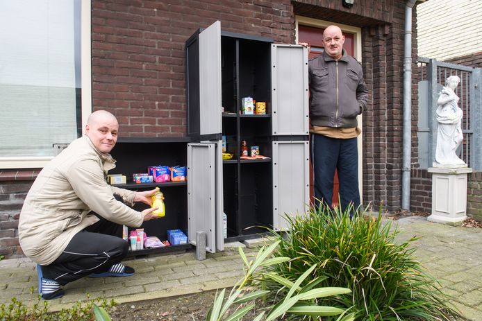 Martien (links) en Martijn van Hout hebben in hun voortuin langs de Ringbaan Oost in Tilburg twee kasten met levensmiddelen en verzorgingsproducten staan. Minima kunnen die gratis meenemen.