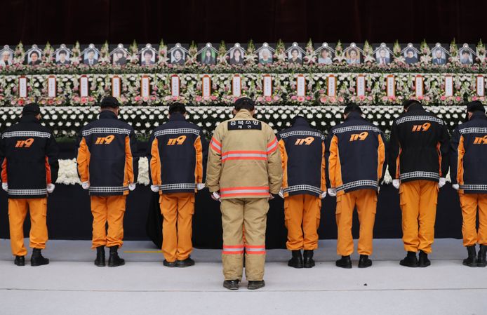 Lokale brandweermannen houden een moment van stilte aan het herinneringsaltaar voor de slachtoffers.