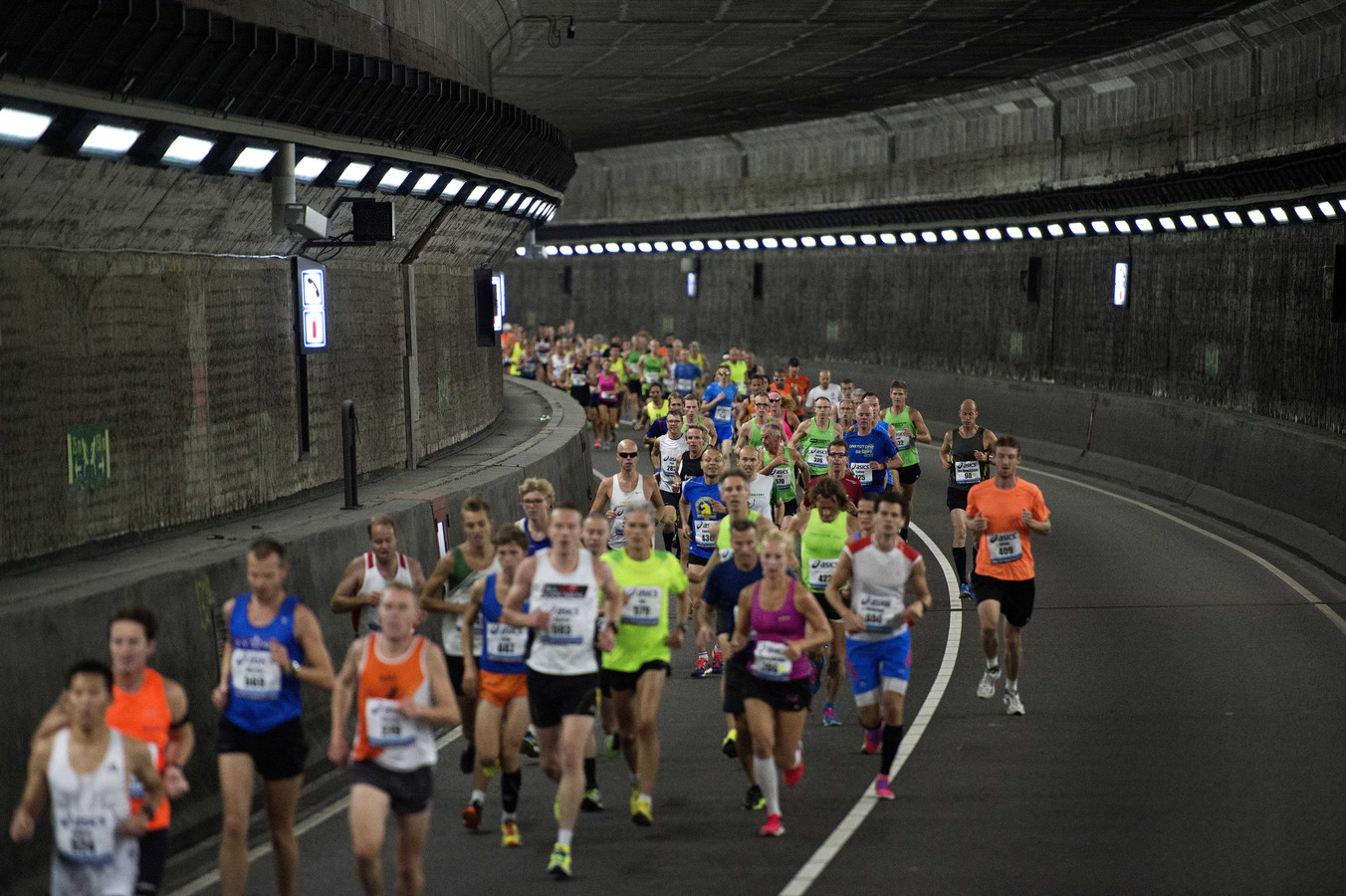 Deelnemers van de Dam tot Dam Loop lopen door de IJ-tunnel richting Zaandam.