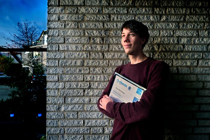 Timo Buitenhuis heeft zijn eerste jaarsalaris aan Unicef gedoneerd, in zijn armen houdt hij een oorkonde van verdienste vast.