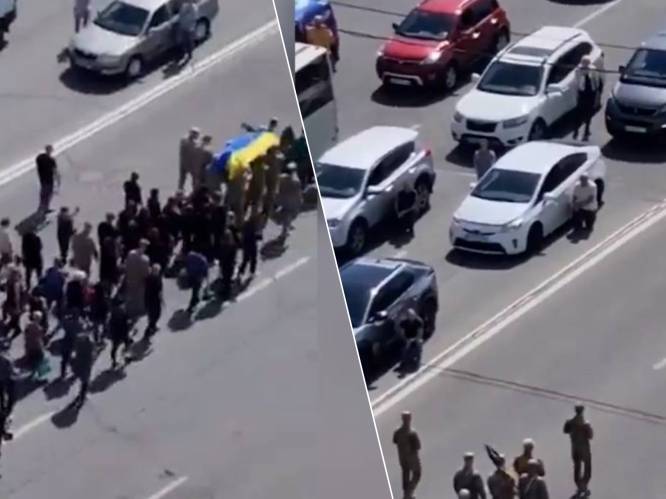 KIJK. Automobilisten in Kiev stappen massaal uit hun wagen tijdens begrafenis van gevallen soldaat 