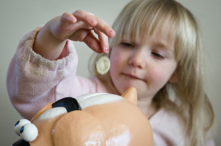 Een meisje stopt geld in haar spaarpot Beeld ANP