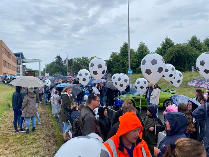 Mensen met voetbalballonnen hebben zich verzameld voor het eerbetoon aan Gino