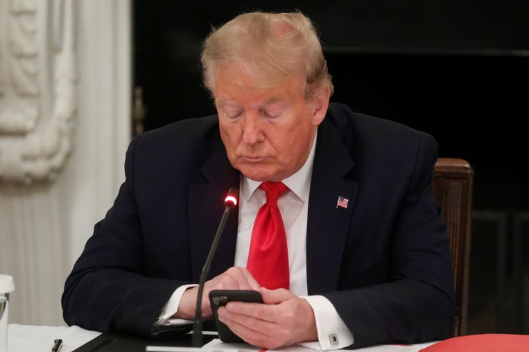 Donald Trump kijkt naar zijn telefoon tijdens een vergadering in het Witte Huis op 18 juni 2020.  Beeld REUTERS
