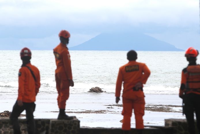 Reddingswerkers kijken naar de vulkaan vanaf een tegenover gelegen strand