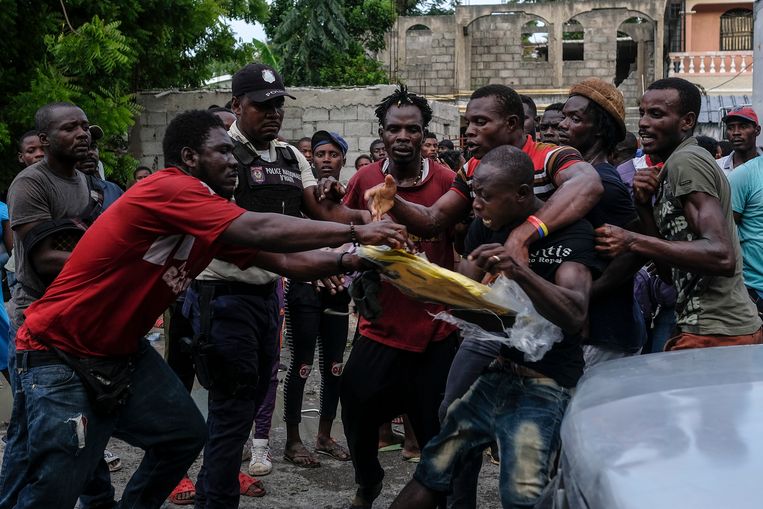 Mannen vechten om een stuk plastic zeil in Les Cayes, dat zwaar getroffen werd door de aardbeving. Beeld AP