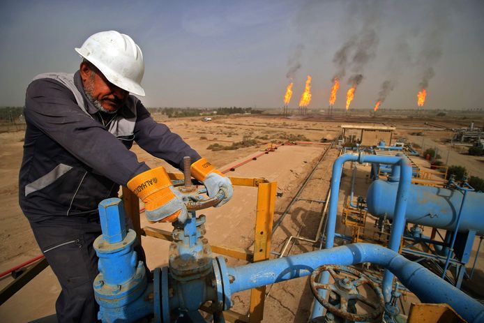 Een technicus draait aan een gaskraan in een olieveld in Irak, waar ook gas gewonnen wordt.