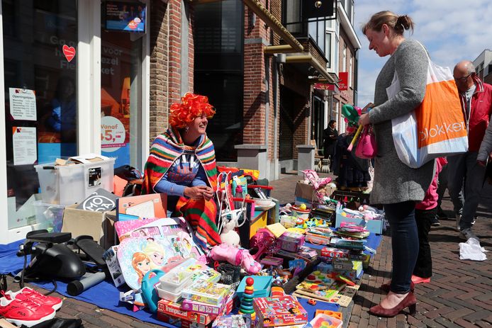 Een kleurrijke verkoopster tussen haar koopwaar op de kleedjesmarkt in Leerdam.