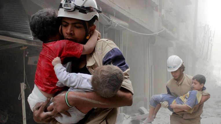 Leden van de hulporganisatie White Helmets redden kinderen in Aleppo. Beeld reuters