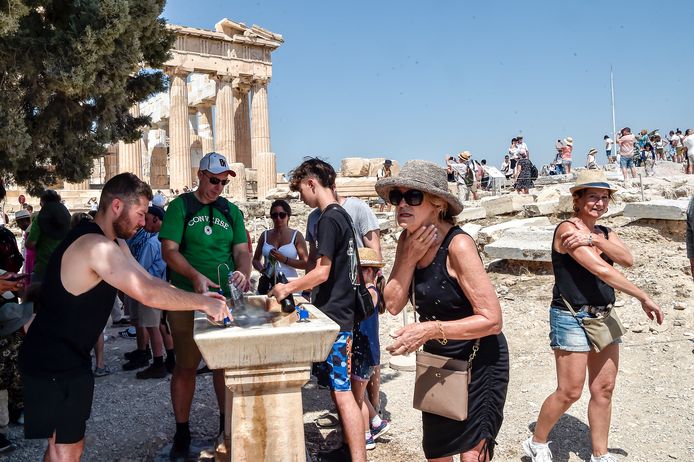 Toeristen zoeken verkoeling bij een drinkfontein in de Akropolis in Athene, Griekenland.
