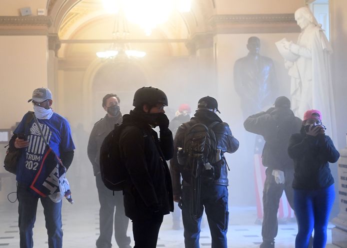 Betogers in het Capitool, de rook van traangas vult samen met hen de kamer.