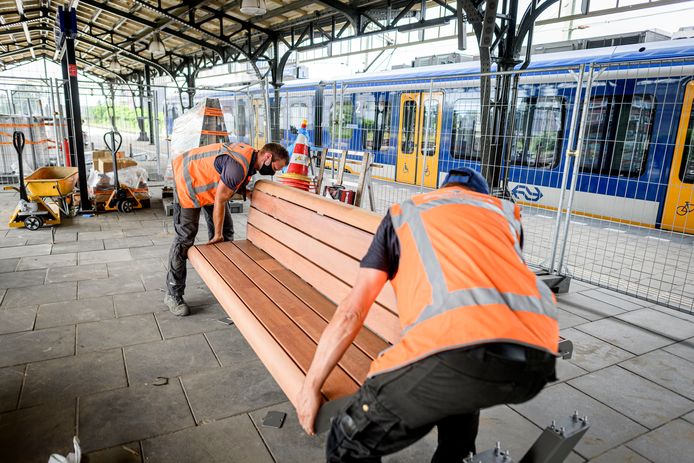 Adriaan Boudestijn (achter) en Jaap Hogedoorn van Streetfurniture plaatsen een nieuwe bank op station Hengelo.