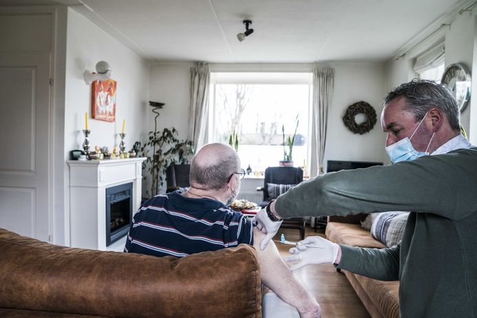 en huisarts vaccineert een man tegen het coronavirus.