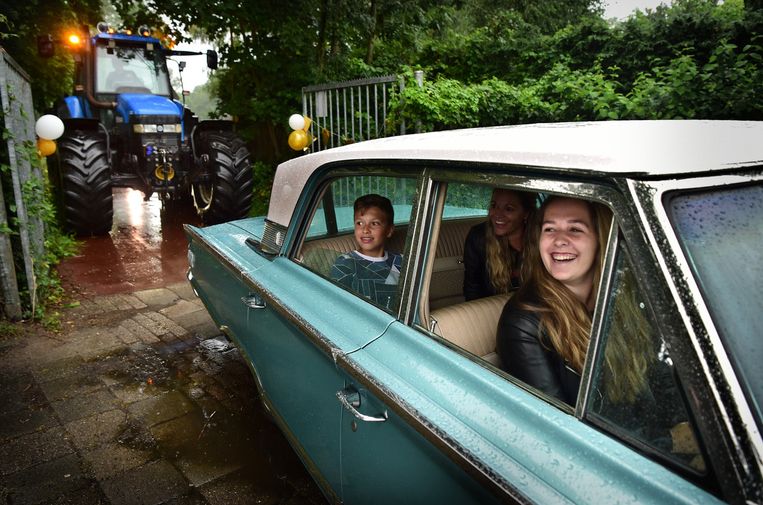 Diploma-uitreiking coronastijl op het Altena College in Sleeuwijk. De geslaagden arriveren met hun familie in een voertuig naar keuze – dat kan een luxe oldtimer zijn, maar evengoed een tractor – en tekenen hun diploma’s onder het afdak van de fietsenstalling.  Beeld Marcel van den Bergh / de Volkskrant 