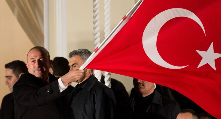 De Turkse buitenlandminister Mevlut Cavusoglu zwaait met een Turkse vlag voor het Turkse consulaat in Hamburg. Beeld AFP