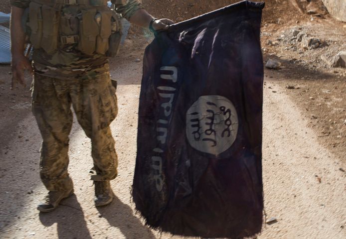 Een lid van de Syrian Democratic Forces toont een buitgemaakte IS-vlag na de val van Raqqa, de Syrische hoofdstad van het IS-kalifaat. Foto uit oktober 2017.