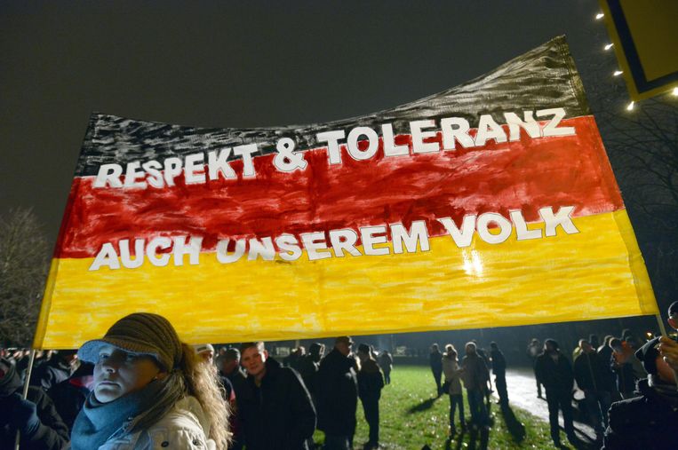 Aanhangers van Pegida houden in Dresden een Duitse vlag omhoog met daarop de tekst: 'Respect en tolerantie ook voor ons volk'. Beeld EPA