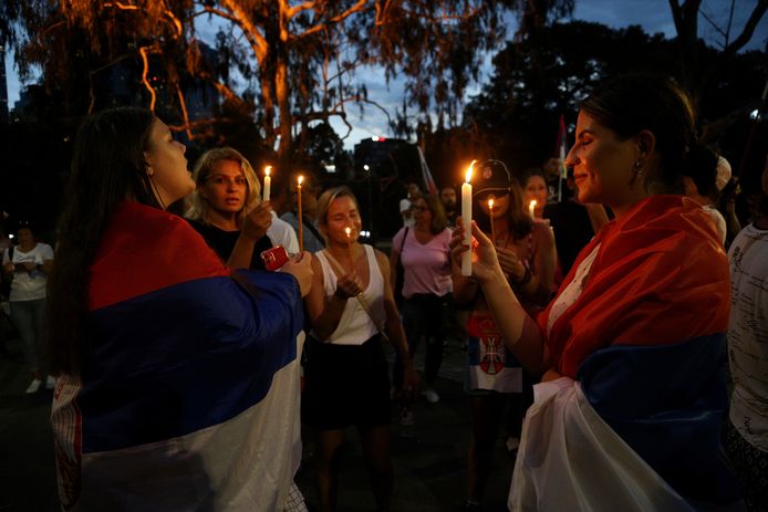 Aanhangers van Novak Djokovic zingen met de Servische vlag om zich heen gedrapeerd liederen en houden kaarsen omhoog aan het hotel in Melbourne waar de toptennisser vast zou worden gehouden.