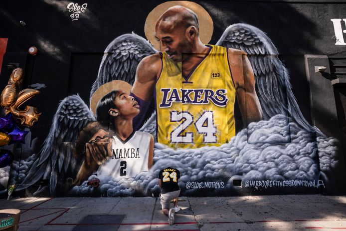 FILE - In this Jan. 26, 2021, file photo, Adam Dergazarian, bottom center, pays his respects for Kobe Bryant and his daughter, Gianna, in front of a mural painted by artist Louie Sloe Palsino in Los Angeles. Federal safety officials are expected to vote Tuesday, Feb. 9, 2021, on what likely caused the helicopter carrying Kobe Bryant, his 13-year-old daughter and seven others to crash into a Southern California hillside last year, killing all aboard. (AP Photo/Jae C. Hong, File)