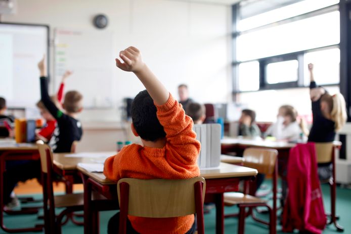 Een jongen steekt zijn hand op tijdens de les, foto ter illustratie.