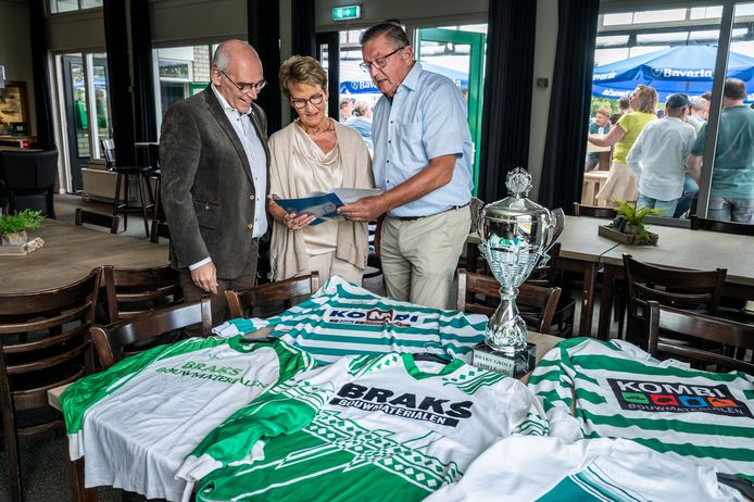Wim Althuizen (l) van de sponsorcommissie bekijkt met Christien en Fons Braks het eerste sponsorcontract. Op tafel liggen de thuisshirts door de jaren heen.