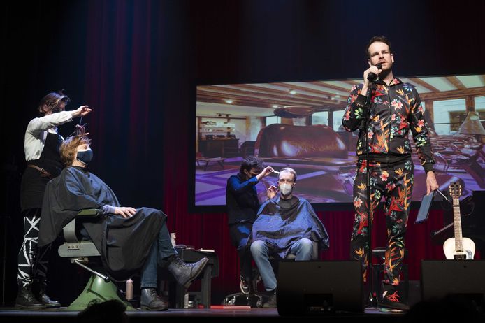 Cabaretier Henri van Loon treedt op in de Kleine Komedie terwijl naast hem geknipt wordt.