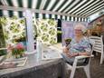 Tropische temperaturen deren Miet van Lieshout uit Lierop niet; de 93-jarige blijft lachen achter haar tijdelijke zonwering.