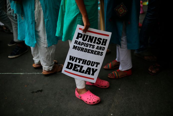 Een Indiase demonstrant houdt een bord vast met de tekst 'straf verkrachters en moordenaar meteen'.