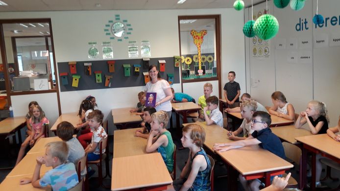 Fauve Hendrickx laat de kinderen uit haar klas het boekje zien dat ze zojuist van wethouder Jan van Hal heeft gekregen.