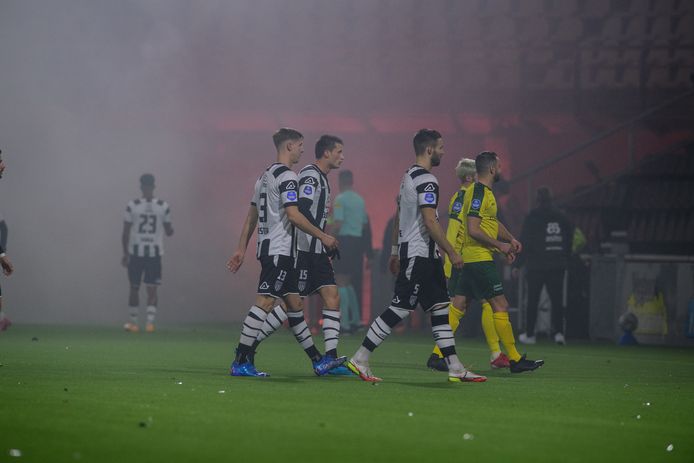 Spelers gaan het veld af na amper vijf minuten nadat supporters vuurwerk hebben afgestoken en er te veel rookontwikkeling is. Later kwamen de fans het stadion binnen.