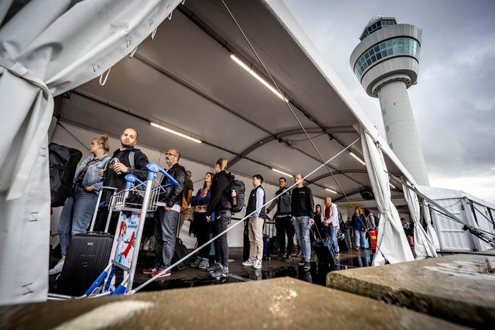 Wachtende reizigers bij een vertrekhal op luchthaven Schiphol.