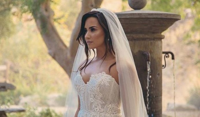 Demi Lovato duikt op in trouwjurk.