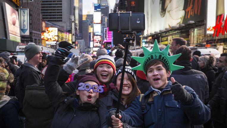A boy wears 2015 glasses as a group of family members use a selfie-stick to photograph themselves during New Year's Eve celebrations in Times Square, New York. Beeld REUTERS