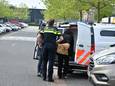Een van de verdachten wordt met papieren zakken om de handen in een politiebusje gezet.