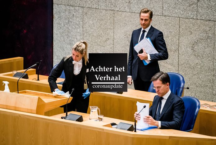 Een kamerbode maakt het spreekgestoelte schoon, minister Hugo de Jonge van Volksgezondheid, Welzijn en Sport (CDA) en premier Mark Rutte tijdens een debat over de ontwikkelingen rond het coronavirus.