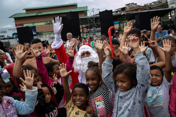 Kinderen omringen de zwarte kerstman in de sloppenwijk Vila Cruzeiro in Rio de Janeiro.