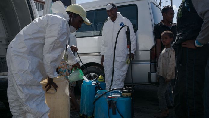Stadsarbeiders vullen containers met ontsmettingsmiddel dat ze zullen verstuiven op de markt van Anisobe in Antananarivo, een van de ongezondste plekken van de stad.