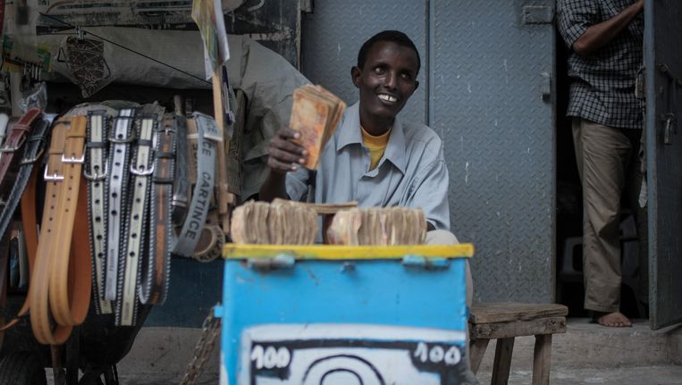 Een geldwisselaar in de Somalische hoofdstad Mogadishu betaalt aan familieleden van migranten die geld hebben opgestuurd. Beeld afp