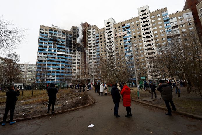 Gevluchte bewoners kijken hoe de brandweer de brand in hun appartementsgebouw in Kiev probeert te blussen.