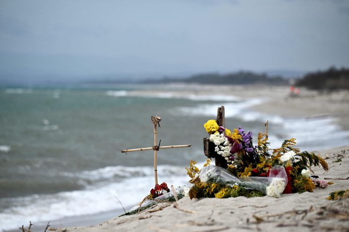 Цветы и крест в память о погибших иммигрантах в последней драме лодки у берегов Италии.  Еще два тела выбросило на берег в эти выходные, через две недели после того, как корабль затонул.
