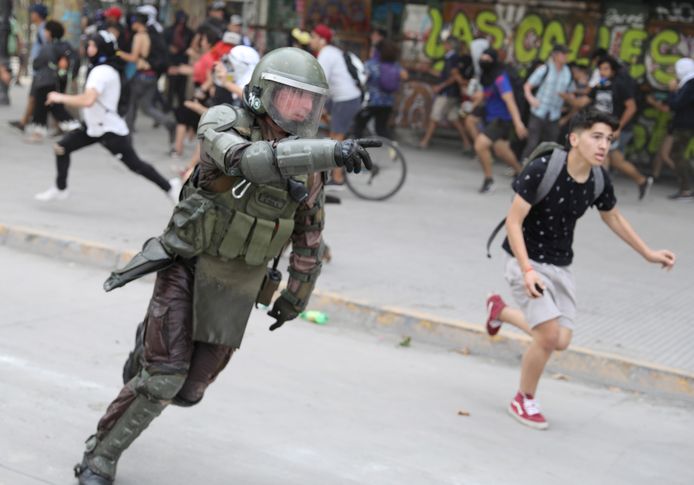 Een politieman achtervolgt demonstranten in Santiago de Chile.