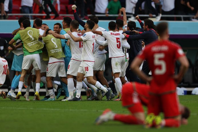 Spelers van Iran vieren feest, terwijl voetballers van Wales treuren na de nederlaag.