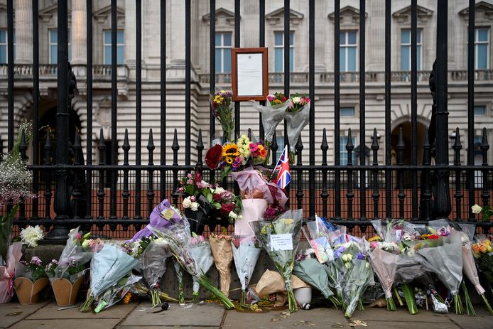 Bloemen worden geplaatst onder het bordje waarop het overlijden van de Queen staat aangekondigd.