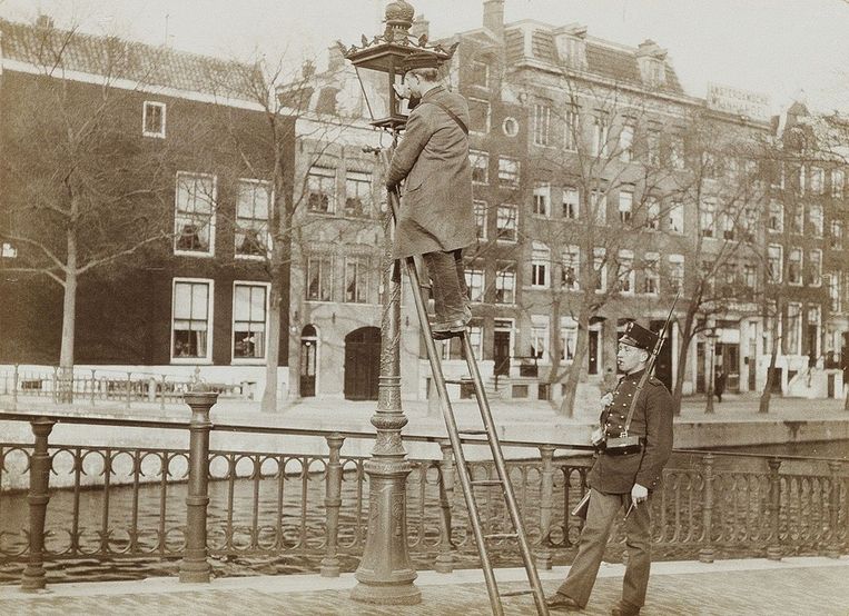 Een lantaarnopsteker op een van de Amsterdamse grachten, in 1903. Opsteker was een nuttig maar zwaar beroep. Beeld Johannes Baptista Bickhoff / Stadsarchief Amsterdam