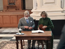Koning Filip en koningin Mathilde tekenen het boek.