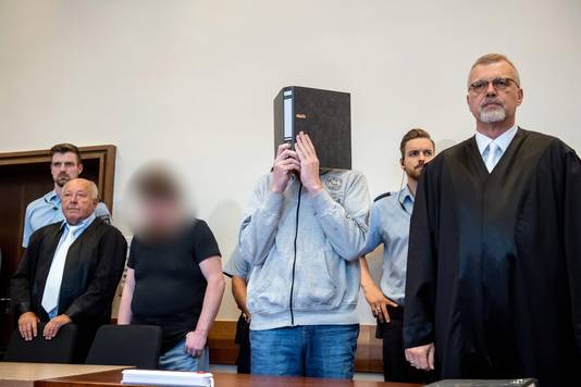 Mario S. en Andreas V. (met map) staan naast hun advocaten tijdens de rechtszaak.
