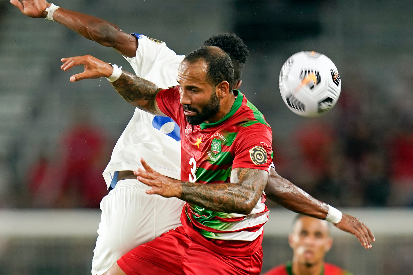 De Surinaamse Ajax-verdediger Sean Klaiber (3) gaat een kopduel aan.