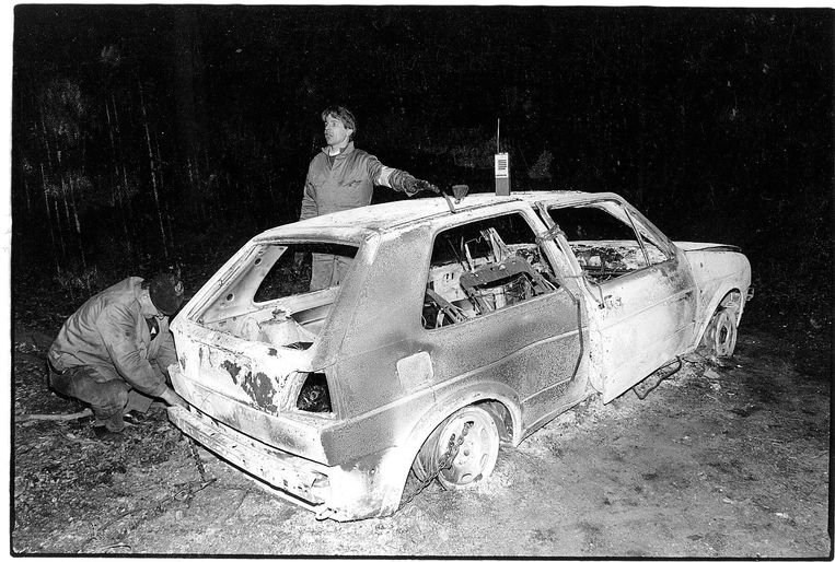 Speurders inspecteren het wrak van een uitgebrande Golf die na de Bende-raid op de Delhaize van Aalst in 1985 werd gevonden.  Beeld rv